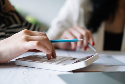 Midsection of woman using calculator