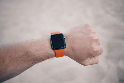 Close-up of hand wearing wristwatch against blurred background