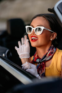 Young woman wearing sunglasses while sitting in car