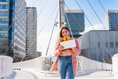 Young woman holding placard walking on footbridge