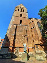 Low angle view of cross by building against blue sky