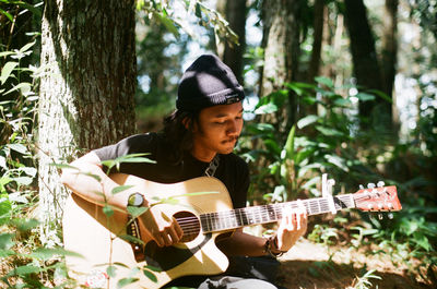 Man playing guitar in forest