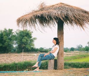 Portrait of young woman sitting on palm tree