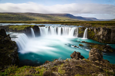 Scenic view of waterfall against sky