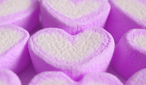 Closeup of pastel purple and white heart shaped marshmallow candies in rows