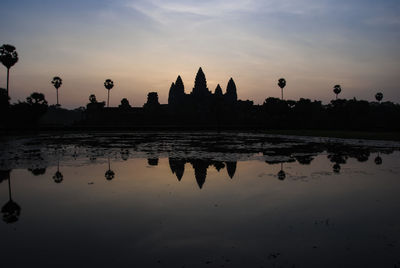 Silhouette of temple at lake during sunset