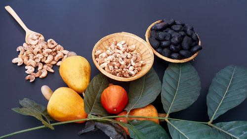 High angle view of cashew with roasted nuts and leaves on table