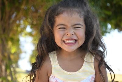 Portrait of cute girl smiling while standing against tree