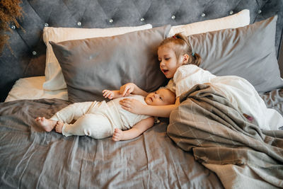 Girl hugs her younger sister on the bed