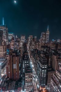 Illuminated modern buildings in city against sky at night