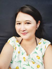 Portrait of smiling young woman against wall