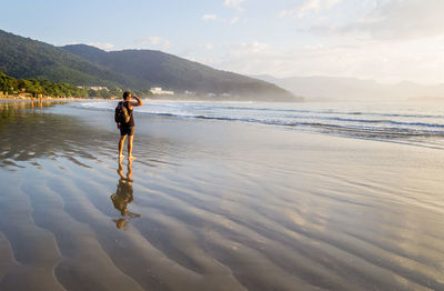 Full length of man standing at beach against sky