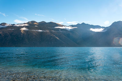 Scenic view of sea and snowcapped mountains against sky