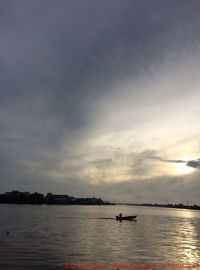 Silhouette person in sea against sky during sunset