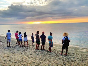 People on beach against sky during sunset