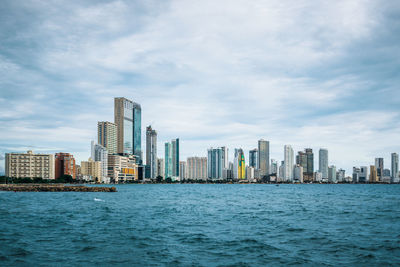 Sea by buildings against sky in city