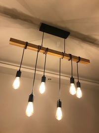 Low angle view of illuminated pendant lights hanging on ceiling