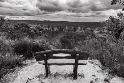 Empty bench on field against sky