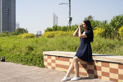 Woman photographing while sitting at park