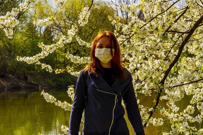 Woman standing by tree against plants