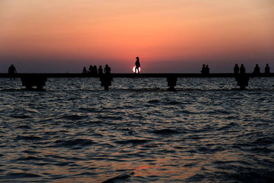 Silhouette of people in sea during sunset