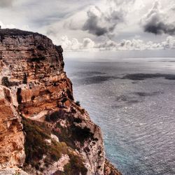 Rock formation by sea against sky