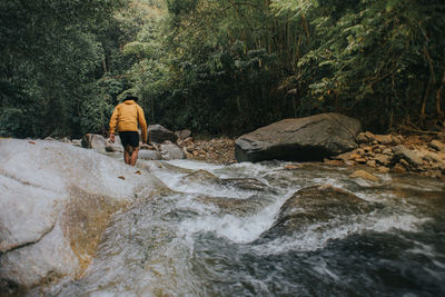 People on rocks by river in forest
