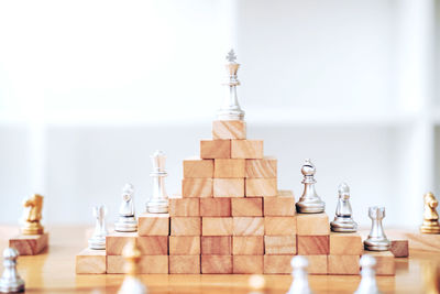 Wooden blocks and chess pieces on table against wall