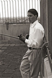 Side view of young man standing on footpath