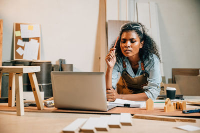 Portrait of young woman using mobile phone at desk in office