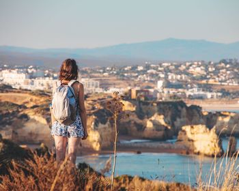 Rear view of woman looking at cityscape against sky