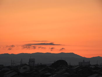 Scenic view of silhouette mountains against orange sky