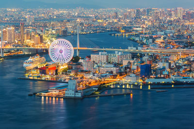 Illuminated ferris wheel in city at waterfront