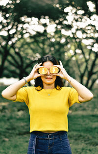 Portrait of young woman standing against yellow tree