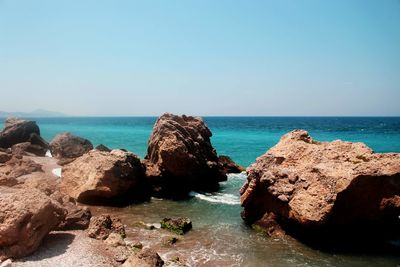 Rocks on sea shore against clear sky