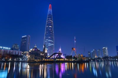 Reflection of the illuminated lotte world tower and lotte magic island.