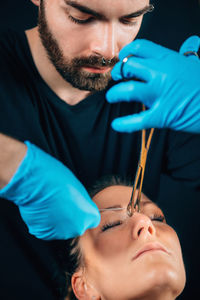 Artist piercing nose of woman in studio