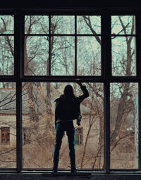 Rear view of man standing by window