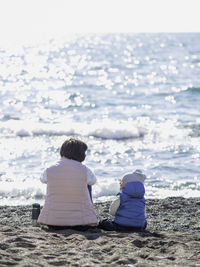 Mother and son relax on pebble beach. woman and toddler on vacation at seaside. mom and child.