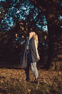 Woman standing by tree in forest