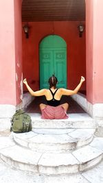 Rear view of woman sitting on door