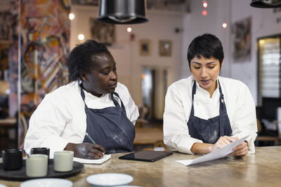 Female colleagues discussing menu card at table in restaurant