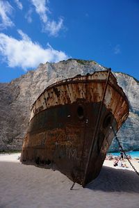 Rusty boat at shore against sky