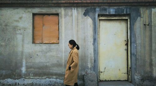 Side view of woman walking by house