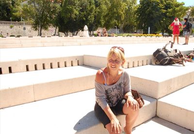 Full length of smiling woman sitting against trees