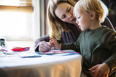 Mother talking with son while sitting at table