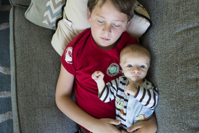 Overhead portrait of baby boy lying with sleeping brother on bed at home