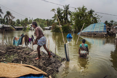 Rear view of people in water against sky