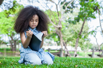 Girl reading book on field