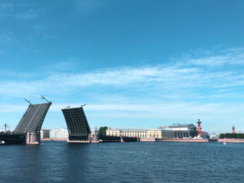 Buildings by river against blue sky